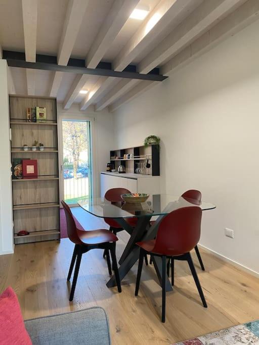 Zona pranzo con tavolo in vetro, cucina a vista e libreria